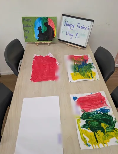 Children's finger paintings and a Happy Father's Day sign set out on a table at Eastwood Blessings