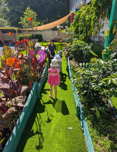 Children walking with an educator along the garden path lined with plants at Eastwood Blessings