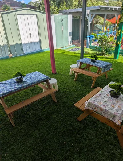 Child-size picnic tables with plants under shade sails in the Eastwood Blessings yard